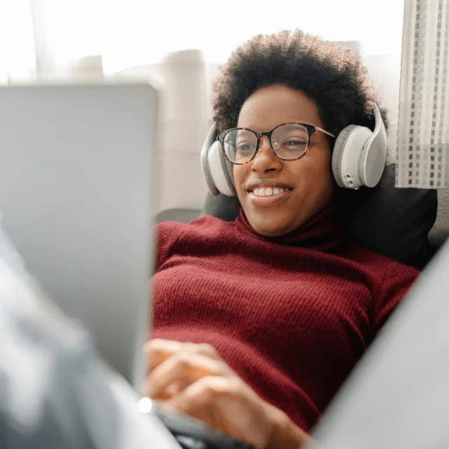 Woman wearing headphones while using laptop