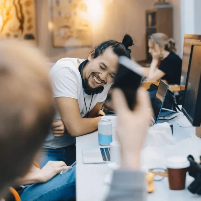 Young man laughing at desk with colleagues